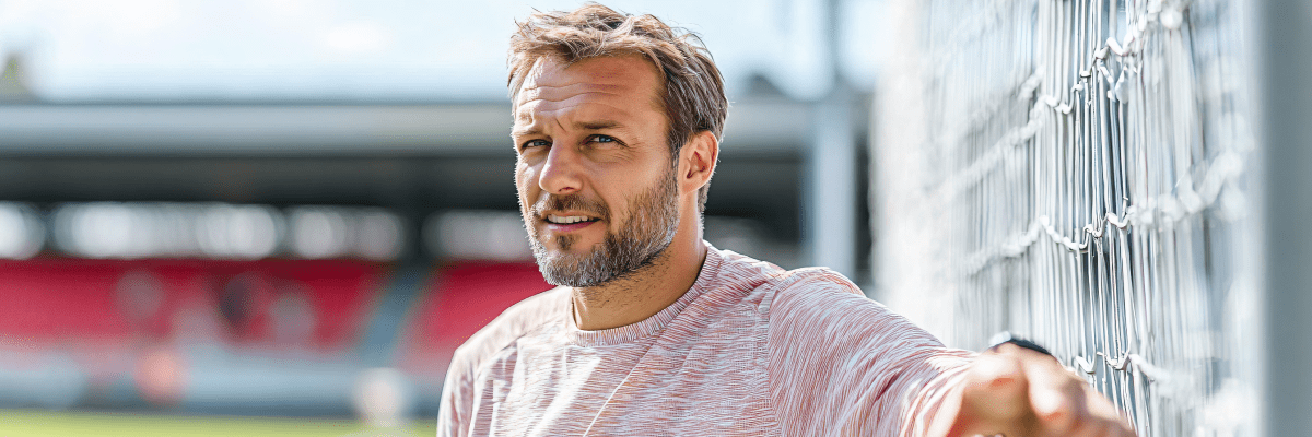 Fußballtrainer lehnt an einem Tor